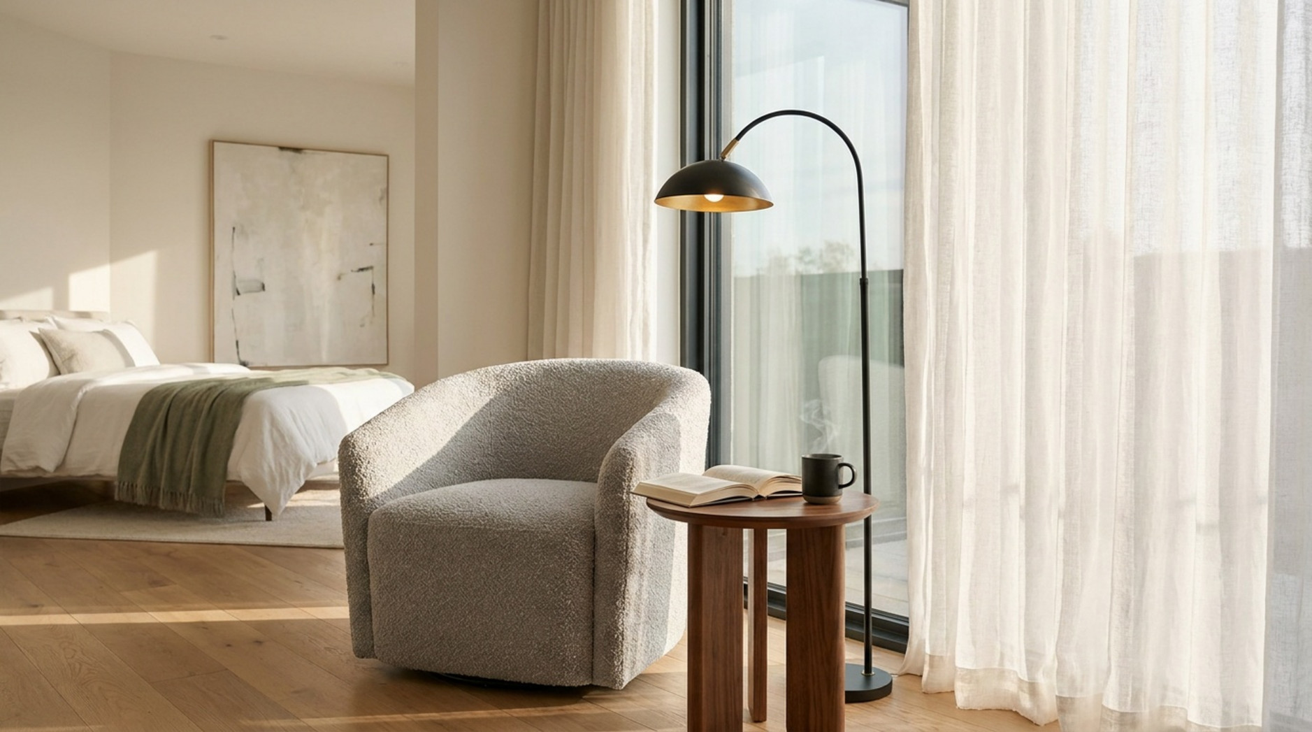 Heller Polstersessel mit rundem Beistelltisch, Buch und schwarzer Stehlampe vor einer großen Fensterfront im Schlafzimmer