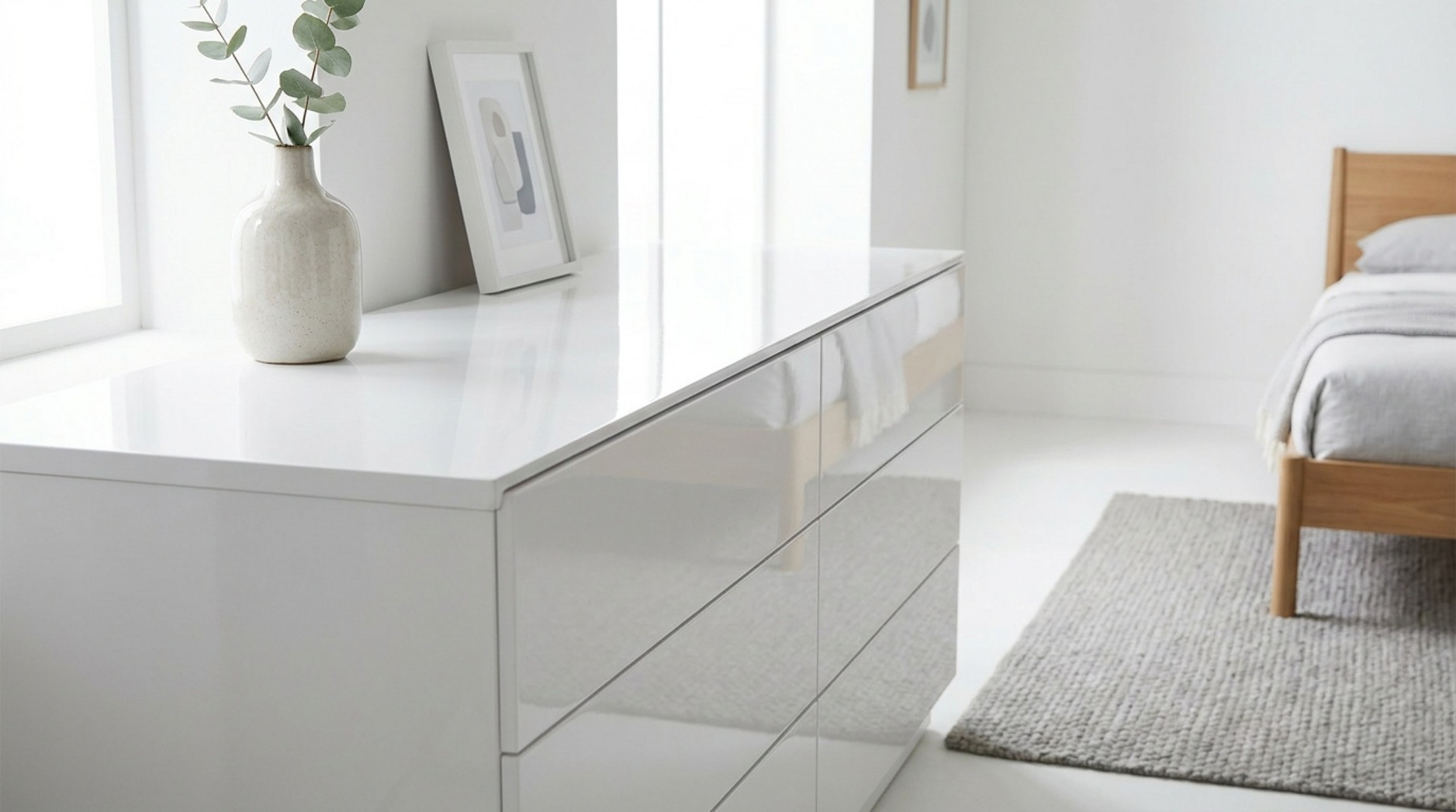 Weiße Hochglanz-Kommode mit Vase und Bildrahmen in einem hellen, minimalistischen Schlafzimmer