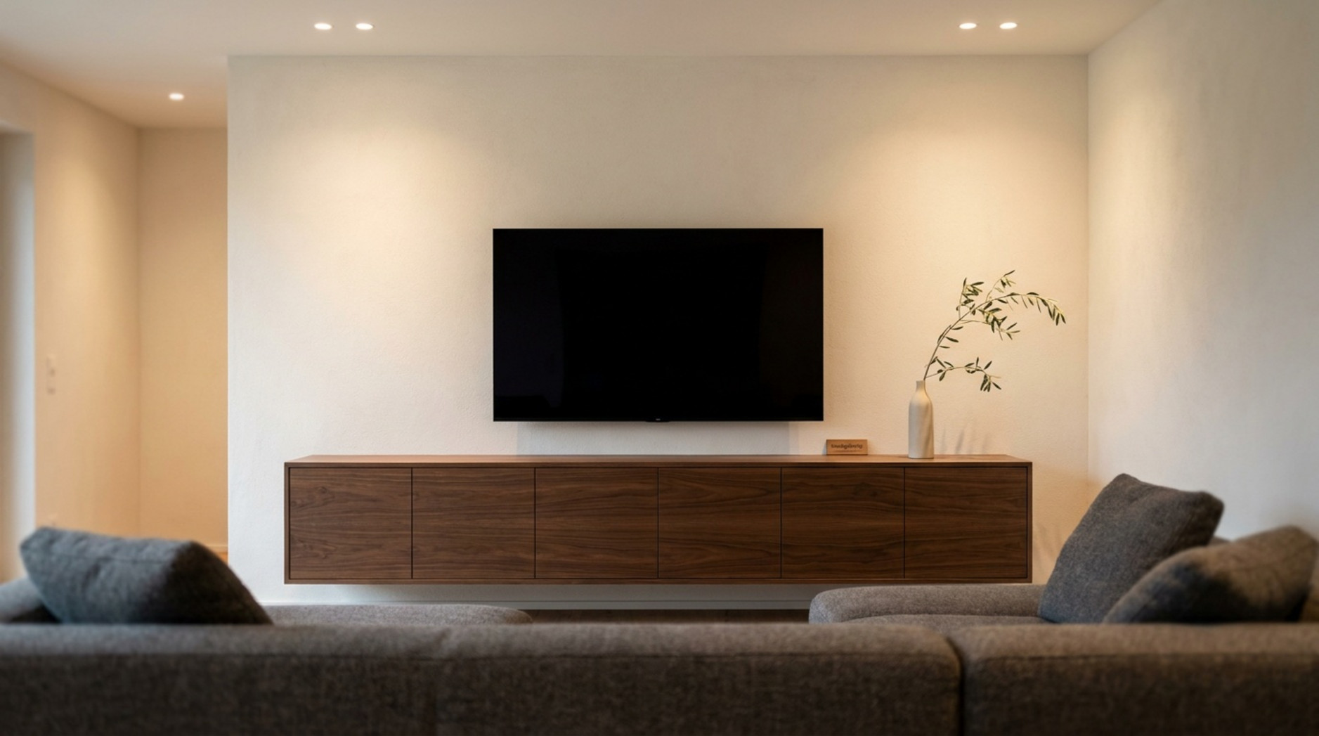 Modernes Wohnzimmer mit wandmontiertem Fernseher, langem Holz-Lowboard und grauem Sofa